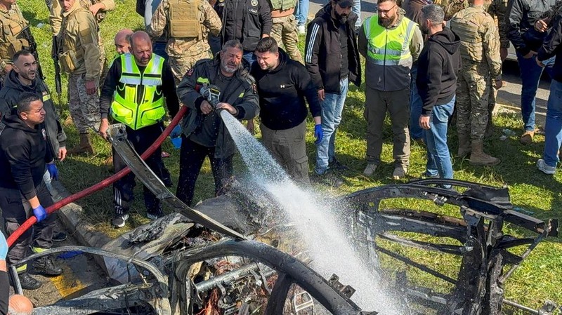 Warga dan pasukan keamanan berkumpul di dekat mobil yang rusak setelah serangan Israel, menurut sumber keamanan, di kota pelabuhan selatan Sidon, Lebanon, 17 Februari 2025. (REUTERS/ALI HANKIR)