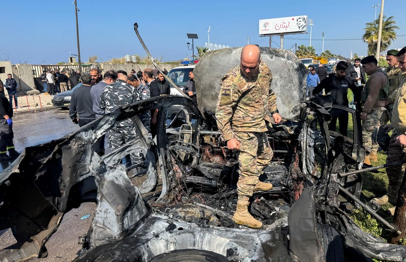 Warga dan pasukan keamanan berkumpul di dekat mobil yang rusak setelah serangan Israel, menurut sumber keamanan, di kota pelabuhan selatan Sidon, Lebanon, 17 Februari 2025. (REUTERS/ALI HANKIR)