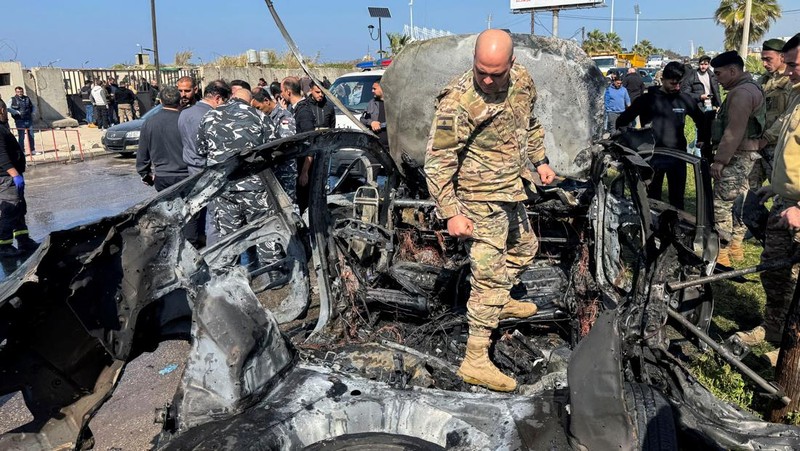 Warga dan pasukan keamanan berkumpul di dekat mobil yang rusak setelah serangan Israel, menurut sumber keamanan, di kota pelabuhan selatan Sidon, Lebanon, 17 Februari 2025. (REUTERS/ALI HANKIR)