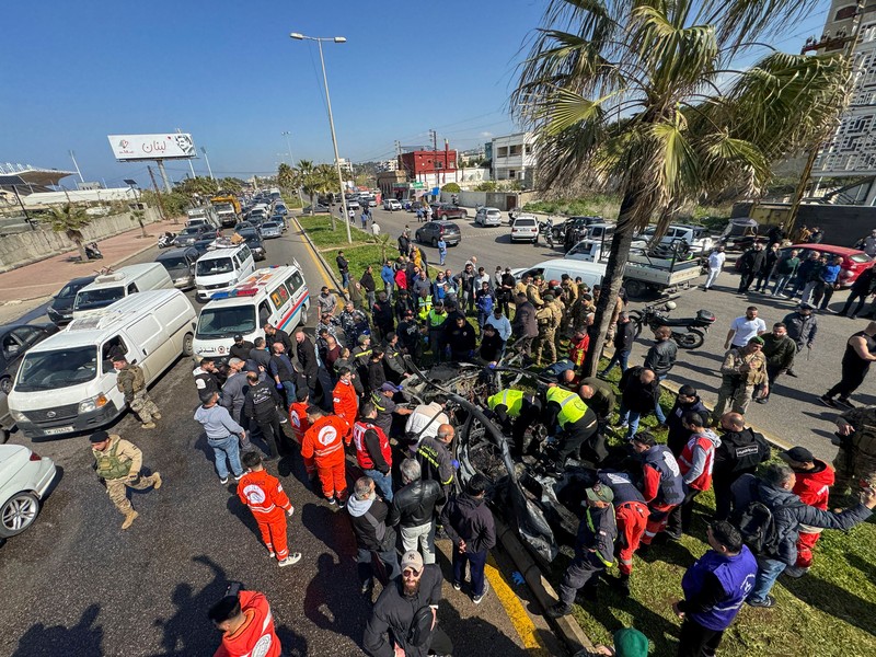 Warga dan pasukan keamanan berkumpul di dekat mobil yang rusak setelah serangan Israel, menurut sumber keamanan, di kota pelabuhan selatan Sidon, Lebanon, 17 Februari 2025. (REUTERS/ALI HANKIR)