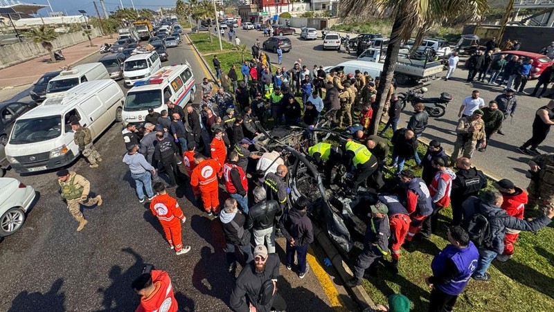 Warga dan pasukan keamanan berkumpul di dekat mobil yang rusak setelah serangan Israel, menurut sumber keamanan, di kota pelabuhan selatan Sidon, Lebanon, 17 Februari 2025. (REUTERS/ALI HANKIR)
