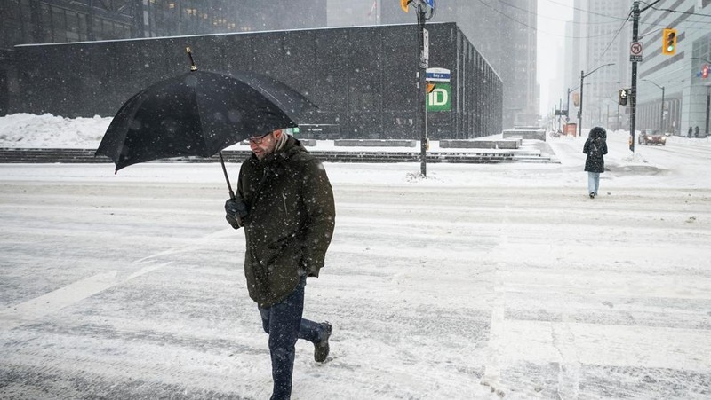Seseorang membersihkan mobilnya dari salju setelah hujan salju lebat di Hamilton, Ontario, Kanada. (REUTERS/Carlos Osorio)