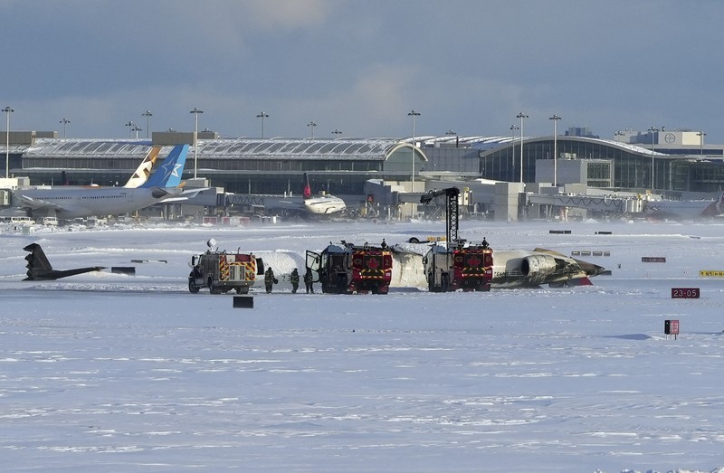 Petugas pemadam kebakaran Bandara Internasional Pearson bekerja pada pesawat Delta Air Lines yang terbalik, yang sedang dalam perjalanan dari Minneapolis ke Toronto ketika jatuh di landasan pacu, di Toronto, Senin, 17 Februari 2025. (Teresa Barbieri/The Canadian Press via AP)