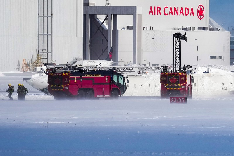 Petugas pemadam kebakaran Bandara Internasional Pearson bekerja pada pesawat Delta Air Lines yang terbalik, yang sedang dalam perjalanan dari Minneapolis ke Toronto ketika jatuh di landasan pacu, di Toronto, Senin, 17 Februari 2025. (Teresa Barbieri/The Canadian Press via AP)