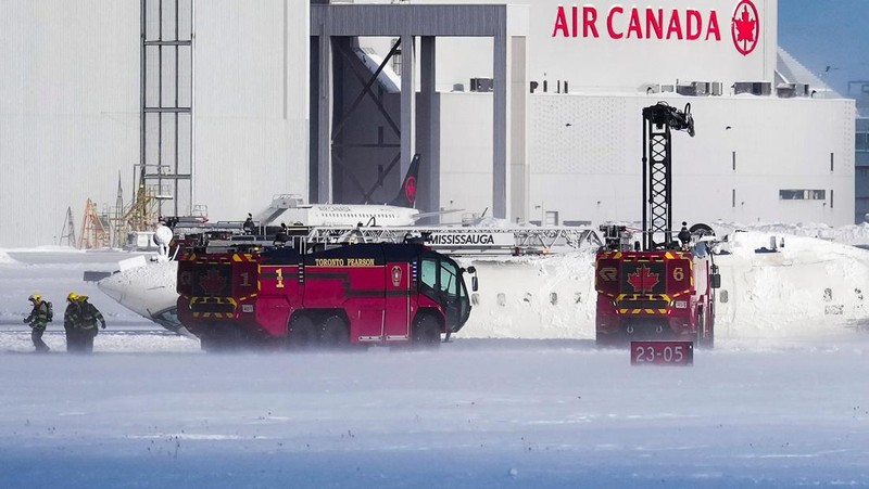 Petugas pemadam kebakaran Bandara Internasional Pearson bekerja pada pesawat Delta Air Lines yang terbalik, yang sedang dalam perjalanan dari Minneapolis ke Toronto ketika jatuh di landasan pacu, di Toronto, Senin, 17 Februari 2025. (Teresa Barbieri/The Canadian Press via AP)