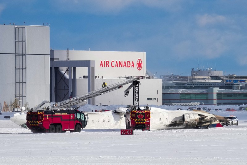 Petugas pemadam kebakaran Bandara Internasional Pearson bekerja pada pesawat Delta Air Lines yang terbalik, yang sedang dalam perjalanan dari Minneapolis ke Toronto ketika jatuh di landasan pacu, di Toronto, Senin, 17 Februari 2025. (Teresa Barbieri/The Canadian Press via AP)