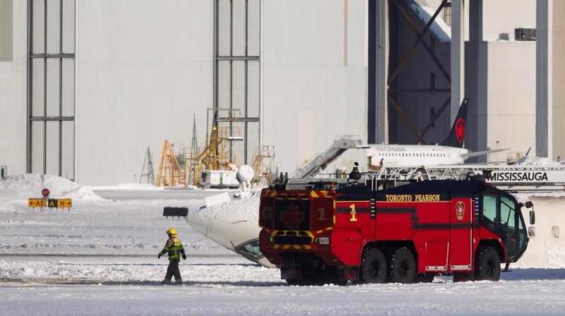 Petugas pemadam kebakaran Bandara Internasional Pearson bekerja pada pesawat Delta Air Lines yang terbalik, yang sedang dalam perjalanan dari Minneapolis ke Toronto ketika jatuh di landasan pacu, di Toronto, Senin, 17 Februari 2025. (Teresa Barbieri/The Canadian Press via AP)