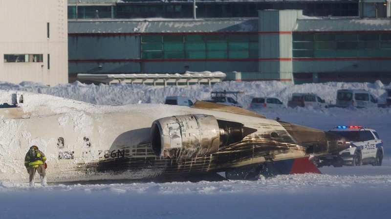 Petugas pemadam kebakaran Bandara Internasional Pearson bekerja pada pesawat Delta Air Lines yang terbalik, yang sedang dalam perjalanan dari Minneapolis ke Toronto ketika jatuh di landasan pacu, di Toronto, Senin, 17 Februari 2025. (Teresa Barbieri/The Canadian Press via AP)