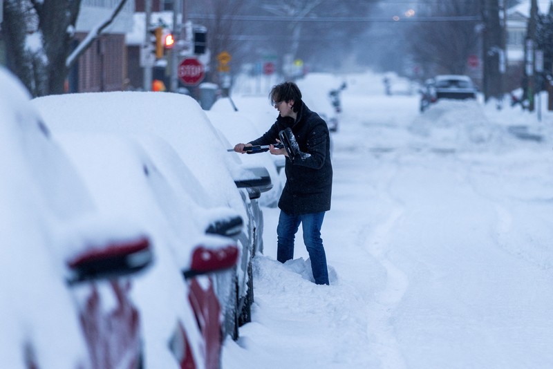 Seseorang membersihkan mobilnya dari salju setelah hujan salju lebat di Hamilton, Ontario, Kanada. (REUTERS/Carlos Osorio)