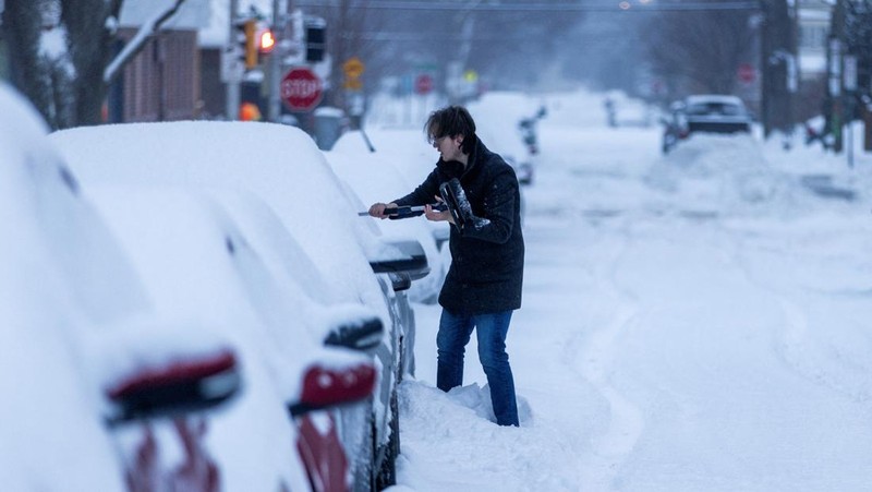 Seseorang membersihkan mobilnya dari salju setelah hujan salju lebat di Hamilton, Ontario, Kanada. (REUTERS/Carlos Osorio)