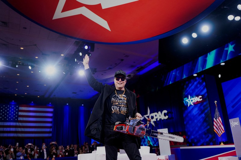 Elon Musk memegang gergaji mesin di atas panggung saat menghadiri Konferensi Aksi Politik Konservatif (CPAC) di National Harbor, Maryland, AS, 20 Februari 2025. (REUTERS/Nathan Howard)