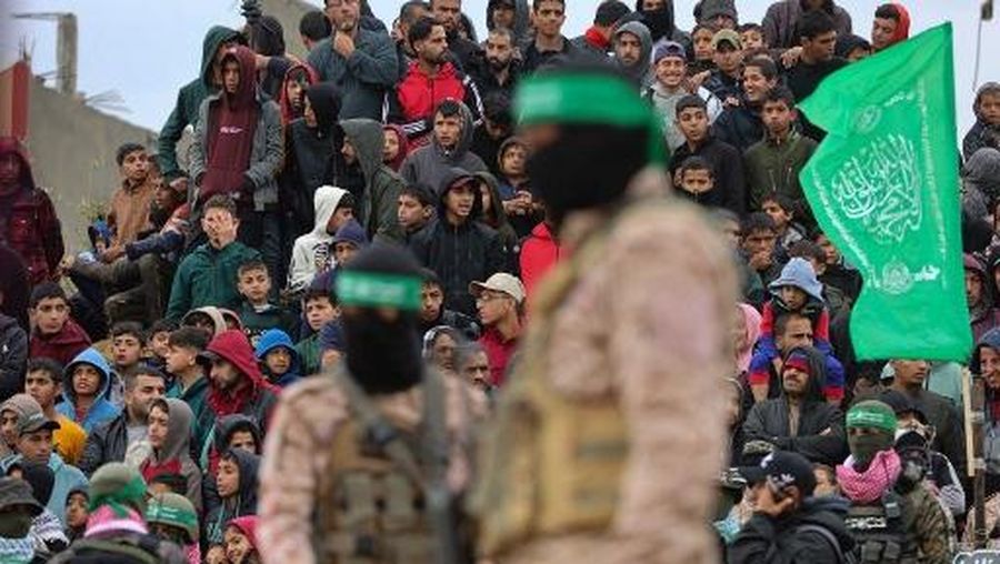 Palestinian Hamas militants stand guard as people gather at the site of the handing over of the bodies of four Israeli hostages in Khan Yunis in the southern Gaza Strip on February 20, 2025. Hamas handed over the bodies of four hostages on February 20, including those of the Bibas family, who have become symbols of the hostage crisis that has gripped Israel since the Gaza war broke out. The transfer of the bodies is the first such handover of remains by Hamas since its October 7, 2023 attack on Israel triggered the war. (Photo by Omar AL-QATTAA / AFP)