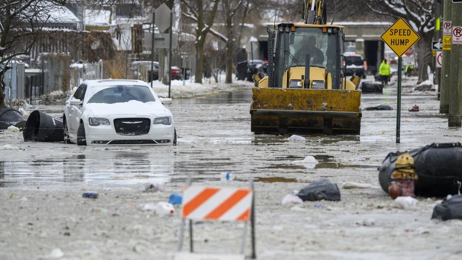 Sebuah truk pemuat depan melaju di Green Street setelah pipa air utama pecah di Detroit yang menyebabkan banjir besar dan memicu evakuasi, Senin, 17 Februari 2025. (Andy Morrison/Detroit News via AP)