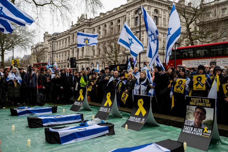 Warga Palestina menyaksikan penyerahan sandera yang telah meninggal, Oded Lifschitz, Shiri Bibas, dan kedua anaknya, Kfir dan Ariel Bibas, yang ditawan dalam serangan mematikan pada 7 Oktober 2023, oleh Hamas kepada Palang Merah sebagai bagian dari gencatan senjata dan kesepakatan pertukaran sandera-tahanan antara Hamas dan Israel, di Khan Younis di Jalur Gaza selatan, 20 Februari 2025. (REUTERS/Ramadan Abed)