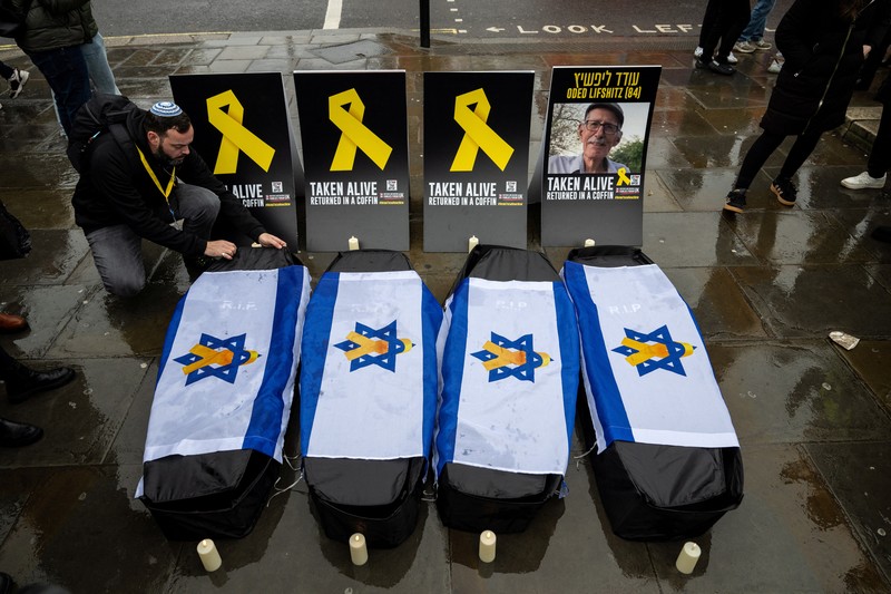 Warga Palestina menyaksikan penyerahan sandera yang telah meninggal, Oded Lifschitz, Shiri Bibas, dan kedua anaknya, Kfir dan Ariel Bibas, yang ditawan dalam serangan mematikan pada 7 Oktober 2023, oleh Hamas kepada Palang Merah sebagai bagian dari gencatan senjata dan kesepakatan pertukaran sandera-tahanan antara Hamas dan Israel, di Khan Younis di Jalur Gaza selatan, 20 Februari 2025. (REUTERS/Ramadan Abed)