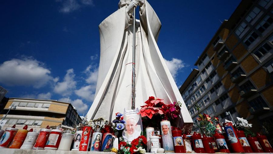 Orang-orang berkumpul untuk berdoa Rosario di patung mendiang Paus Yohanes Paulus II di luar Rumah Sakit Gemelli, tempat Paus Fransiskus dirawat, di Roma, Italia, 22 Februari 2025. (REUTERS/Vincenzo Livieri)