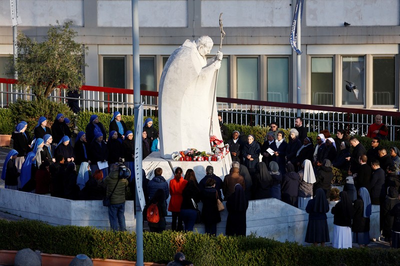 Orang-orang berkumpul untuk berdoa Rosario di patung mendiang Paus Yohanes Paulus II di luar Rumah Sakit Gemelli, tempat Paus Fransiskus dirawat, di Roma, Italia, 22 Februari 2025. Orang-orang berkumpul untuk berdoa Rosario di patung mendiang Paus Yohanes Paulus II di luar Rumah Sakit Gemelli, tempat Paus Fransiskus dirawat, di Roma, Italia, 22 Februari 2025. (REUTERS/Vincenzo Livieri)