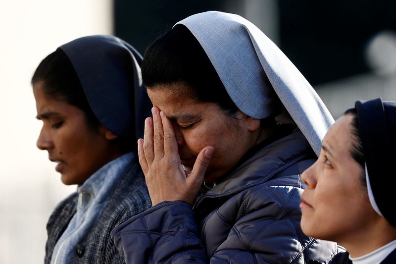 Orang-orang berkumpul untuk berdoa Rosario di patung mendiang Paus Yohanes Paulus II di luar Rumah Sakit Gemelli, tempat Paus Fransiskus dirawat, di Roma, Italia, 22 Februari 2025. (REUTERS/Vincenzo Livieri)