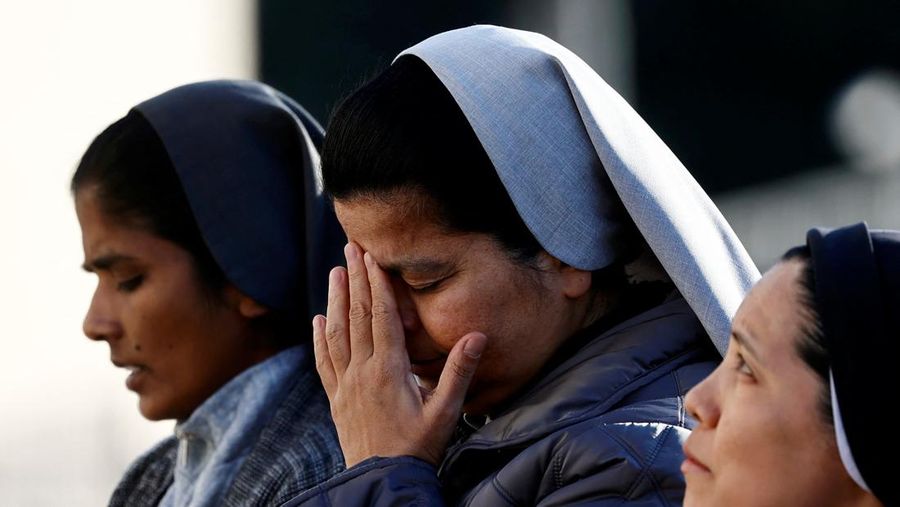 Orang-orang berkumpul untuk berdoa Rosario di patung mendiang Paus Yohanes Paulus II di luar Rumah Sakit Gemelli, tempat Paus Fransiskus dirawat, di Roma, Italia, 22 Februari 2025. (REUTERS/Vincenzo Livieri)