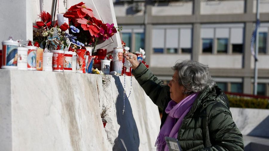 Orang-orang berkumpul untuk berdoa Rosario di patung mendiang Paus Yohanes Paulus II di luar Rumah Sakit Gemelli, tempat Paus Fransiskus dirawat, di Roma, Italia, 22 Februari 2025. (REUTERS/Vincenzo Livieri)