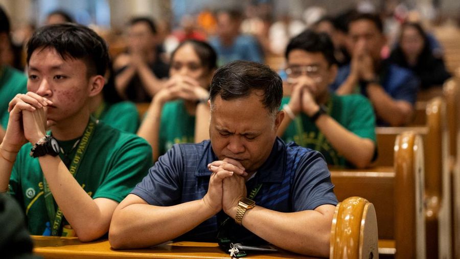 Orang-orang berkumpul untuk berdoa Rosario di patung mendiang Paus Yohanes Paulus II di luar Rumah Sakit Gemelli, tempat Paus Fransiskus dirawat, di Roma, Italia, 22 Februari 2025. (REUTERS/Vincenzo Livieri)