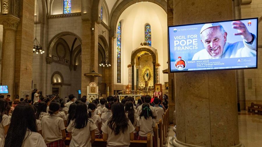 Orang-orang berkumpul untuk berdoa Rosario di patung mendiang Paus Yohanes Paulus II di luar Rumah Sakit Gemelli, tempat Paus Fransiskus dirawat, di Roma, Italia, 22 Februari 2025. (REUTERS/Vincenzo Livieri)