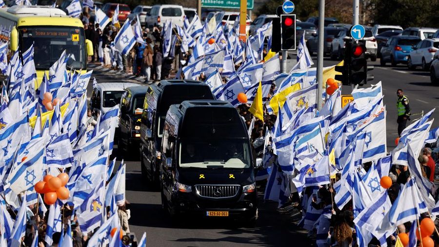 Warga Israel mengibarkan bendera Israel saat konvoi yang membawa peti jenazah Shiri, 32 tahun, dan kedua anaknya Kfir, 9 bulan, dan Ariel, 4 tahun, dari keluarga Bibas, yang diculik dari rumah mereka di Kibbutz Nir Oz selama serangan mematikan pada 7 Oktober 2023 oleh Hamas dan kemudian dibunuh di Gaza, berjalan sebagai bagian dari prosesi pemakaman mereka di Ashkelon, Israel, 26 Februari 2025. (REUTERS/Amir Cohen)