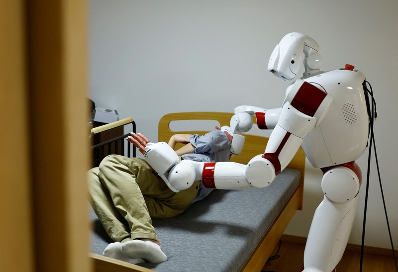 AIREC, robot humanoid yang digerakkan oleh kecerdasan buatan (AI), mendemonstrasikan manuver untuk mengganti popok atau mencegah luka baring dengan seorang peneliti di laboratorium Universitas Waseda di Tokyo, Jepang. (REUTERS/Kim Kyung-Hoon) AIREC, robot humanoid yang digerakkan oleh kecerdasan buatan (AI), mendemonstrasikan manuver untuk mengganti popok atau mencegah luka baring dengan seorang peneliti di laboratorium Universitas Waseda di Tokyo, Jepang. (REUTERS/Kim Kyung-Hoon)