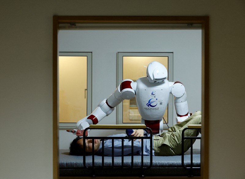 AIREC, robot humanoid yang digerakkan oleh kecerdasan buatan (AI), mendemonstrasikan manuver untuk mengganti popok atau mencegah luka baring dengan seorang peneliti di laboratorium Universitas Waseda di Tokyo, Jepang. (REUTERS/Kim Kyung-Hoon) AIREC, robot humanoid yang digerakkan oleh kecerdasan buatan (AI), mendemonstrasikan manuver untuk mengganti popok atau mencegah luka baring dengan seorang peneliti di laboratorium Universitas Waseda di Tokyo, Jepang. (REUTERS/Kim Kyung-Hoon)