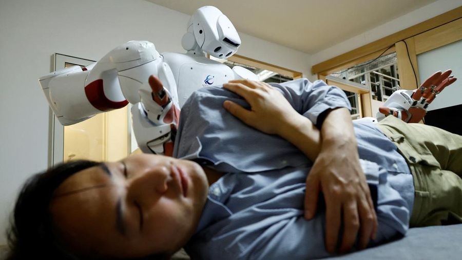 AIREC, robot humanoid yang digerakkan oleh kecerdasan buatan (AI), mendemonstrasikan manuver untuk mengganti popok atau mencegah luka baring dengan seorang peneliti di laboratorium Universitas Waseda di Tokyo, Jepang. (REUTERS/Kim Kyung-Hoon)