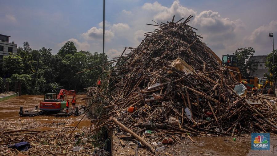 Petugas Dinas Lingkungan Hidup DKI Jakarta menggunakan alat berat saat membersihkan sampah di Saringan Sampah TB Simatupang (SSTBS), Jakarta, Senin (3/3/2025). (CNBC Indonesia/Faisal Rahman)