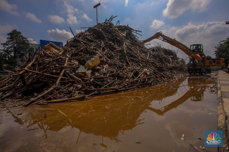 Petugas Dinas Lingkungan Hidup DKI Jakarta menggunakan alat berat saat membersihkan sampah di Saringan Sampah TB Simatupang (SSTBS), Jakarta, Senin (3/3/2025). (CNBC Indonesia/Faisal Rahman)