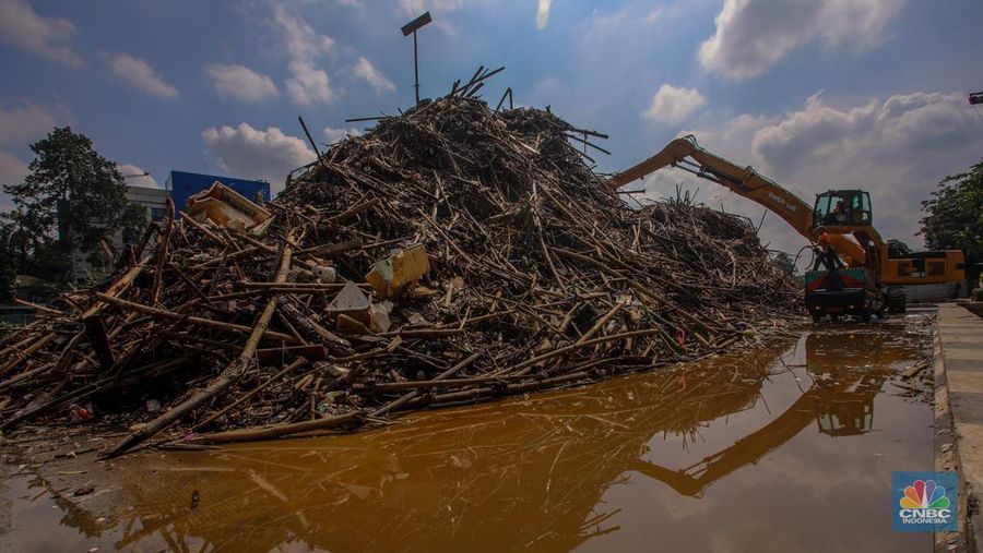Petugas Dinas Lingkungan Hidup DKI Jakarta menggunakan alat berat saat membersihkan sampah di Saringan Sampah TB Simatupang (SSTBS), Jakarta, Senin (3/3/2025). (CNBC Indonesia/Faisal Rahman)
