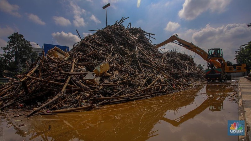 Petugas Dinas Lingkungan Hidup DKI Jakarta menggunakan alat berat saat membersihkan sampah di Saringan Sampah TB Simatupang (SSTBS), Jakarta, Senin (3/3/2025). (CNBC Indonesia/Faisal Rahman)
