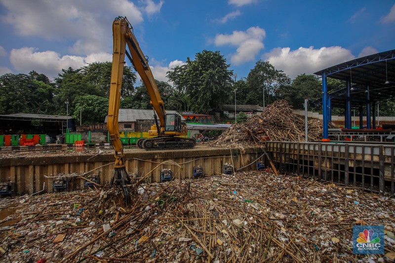 Petugas Dinas Lingkungan Hidup DKI Jakarta menggunakan alat berat saat membersihkan sampah di Saringan Sampah TB Simatupang (SSTBS), Jakarta, Senin (3/3/2025). (CNBC Indonesia/Faisal Rahman)
