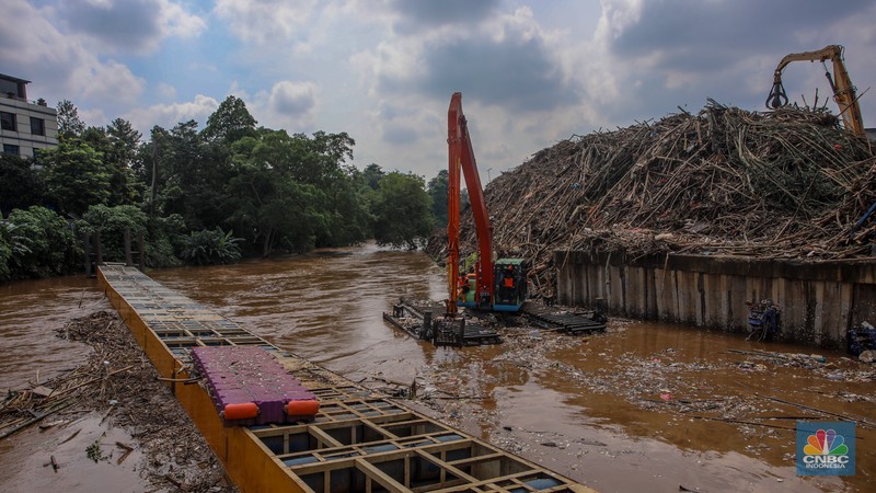 Petugas Dinas Lingkungan Hidup DKI Jakarta menggunakan alat berat saat membersihkan sampah di Saringan Sampah TB Simatupang (SSTBS), Jakarta, Senin (3/3/2025). (CNBC Indonesia/Faisal Rahman)
