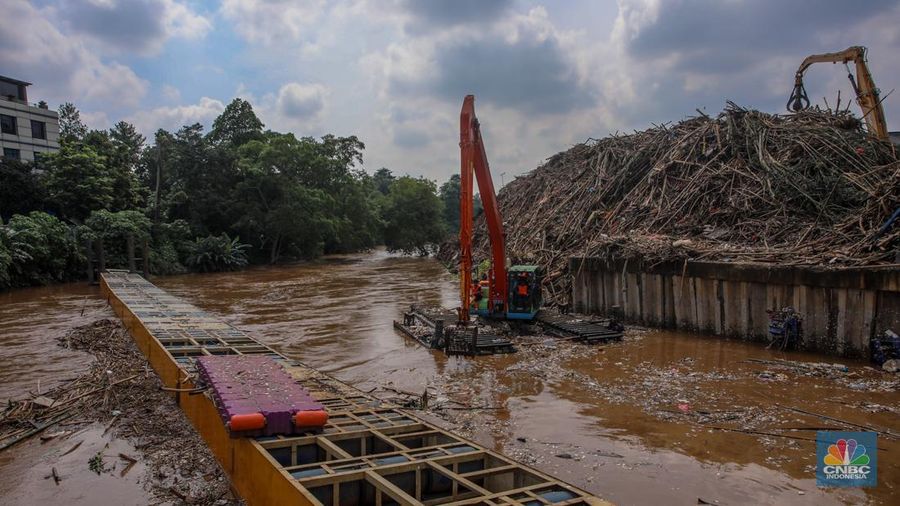 Petugas Dinas Lingkungan Hidup DKI Jakarta menggunakan alat berat saat membersihkan sampah di Saringan Sampah TB Simatupang (SSTBS), Jakarta, Senin (3/3/2025). (CNBC Indonesia/Faisal Rahman)