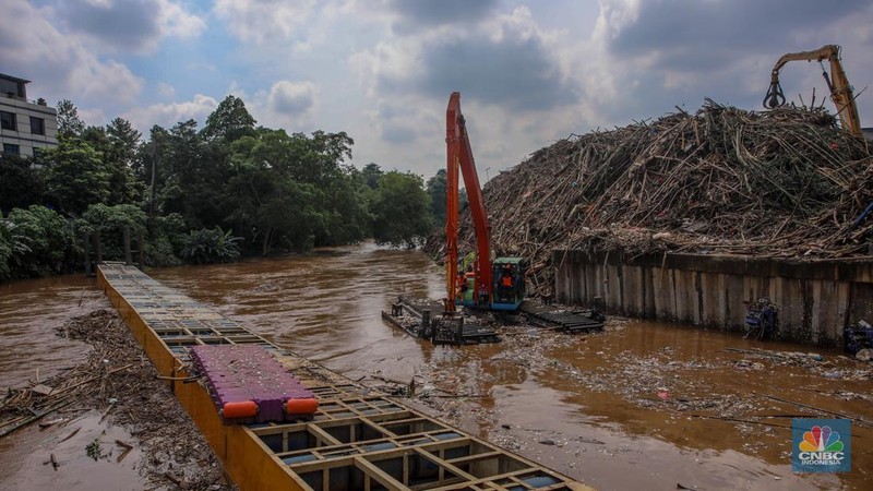 Petugas Dinas Lingkungan Hidup DKI Jakarta menggunakan alat berat saat membersihkan sampah di Saringan Sampah TB Simatupang (SSTBS), Jakarta, Senin (3/3/2025). (CNBC Indonesia/Faisal Rahman)