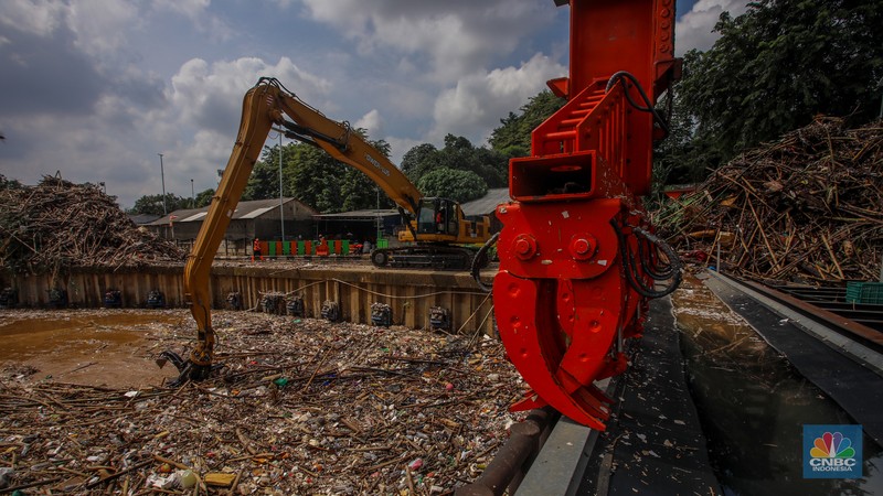 Petugas Dinas Lingkungan Hidup DKI Jakarta menggunakan alat berat saat membersihkan sampah di Saringan Sampah TB Simatupang (SSTBS), Jakarta, Senin (3/3/2025). (CNBC Indonesia/Faisal Rahman)