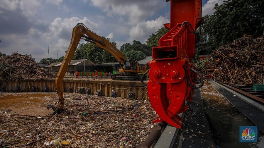 Petugas Dinas Lingkungan Hidup DKI Jakarta menggunakan alat berat saat membersihkan sampah di Saringan Sampah TB Simatupang (SSTBS), Jakarta, Senin (3/3/2025). (CNBC Indonesia/Faisal Rahman)