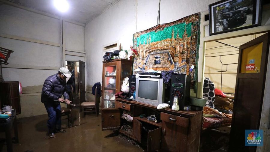Seorang warga membersihkan rumah dari sisa-sisa banjir bandang di Desa Citeko, Kecamatan Cisarua, Jawa Barat, Senin (3/3/2025). (CNBC Indonesia/Tri Susilo)