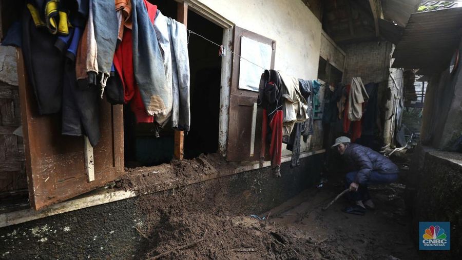 Seorang warga membersihkan rumah dari sisa-sisa banjir bandang di Desa Citeko, Kecamatan Cisarua, Jawa Barat, Senin (3/3/2025). (CNBC Indonesia/Tri Susilo)