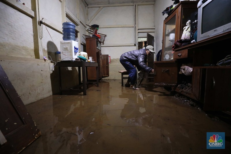 Seorang warga membersihkan rumah dari sisa-sisa banjir bandang di Desa Citeko, Kecamatan Cisarua, Jawa Barat, Senin (3/3/2025). (CNBC Indonesia/Tri Susilo)