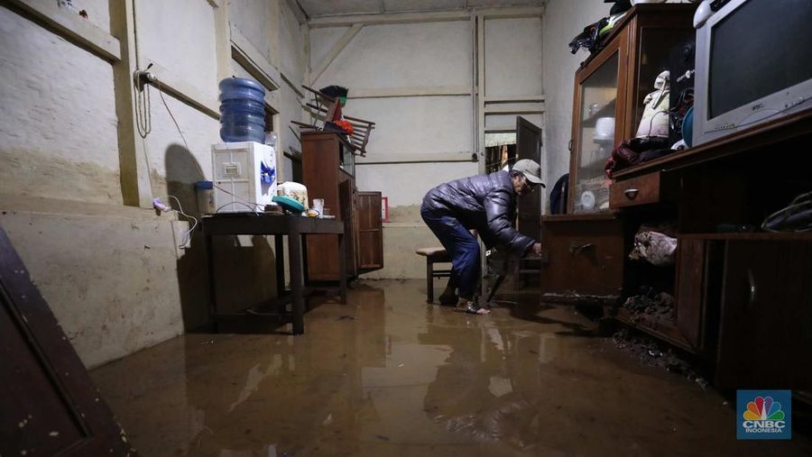 Seorang warga membersihkan rumah dari sisa-sisa banjir bandang di Desa Citeko, Kecamatan Cisarua, Jawa Barat, Senin (3/3/2025). (CNBC Indonesia/Tri Susilo)