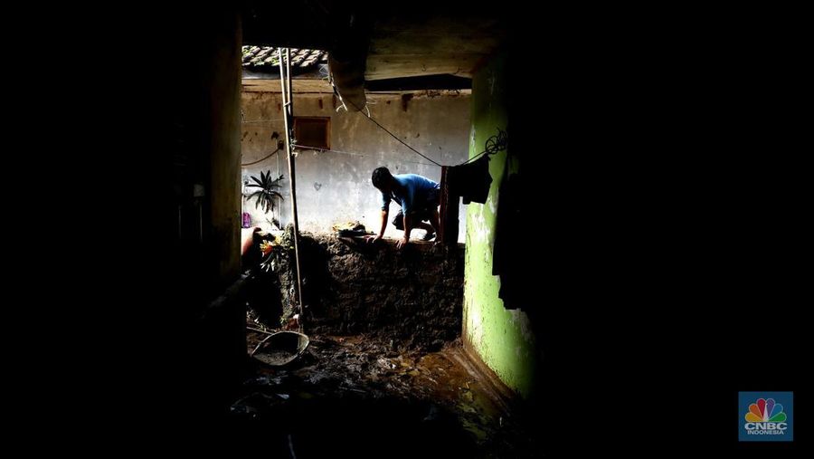 Seorang warga membersihkan rumah dari sisa-sisa banjir bandang di Desa Citeko, Kecamatan Cisarua, Jawa Barat, Senin (3/3/2025). (CNBC Indonesia/Tri Susilo)