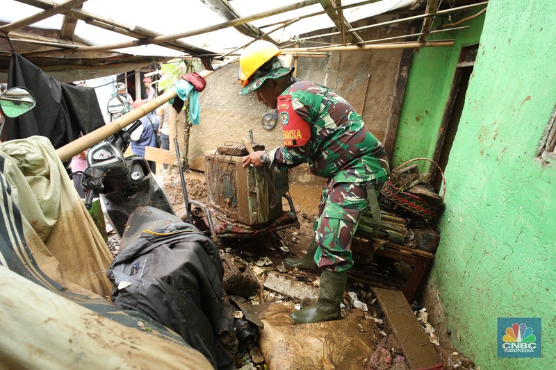 Warga membersihkan sisa-sisa lumpur dan sampah banjir yang melanda Kampung Pensiunan, Desa Tugu Selatan, Kecamatan Cisarua, Kabupaten Bogor, Jawa Barat, Senin (3/3/2025). (CNBC Indonesia/Tri Susilo)