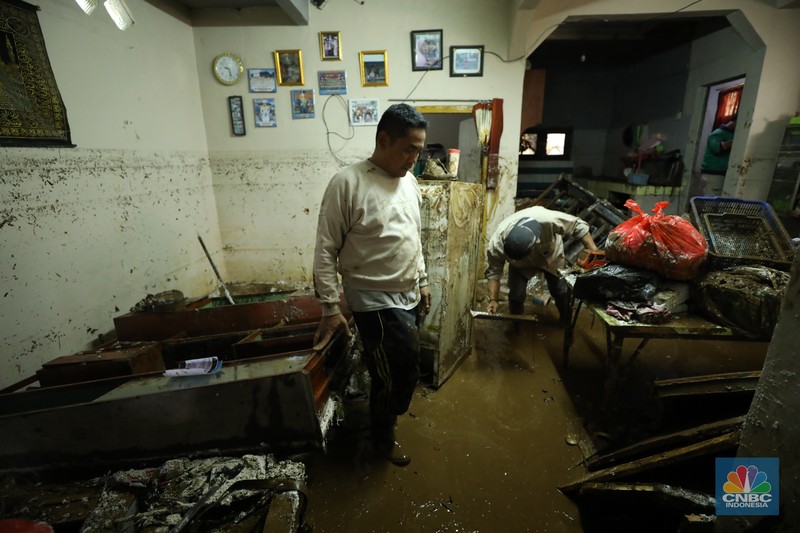 Warga membersihkan sisa-sisa lumpur dan sampah banjir yang melanda Kampung Pensiunan, Desa Tugu Selatan, Kecamatan Cisarua, Kabupaten Bogor, Jawa Barat, Senin (3/3/2025). (CNBC Indonesia/Tri Susilo)