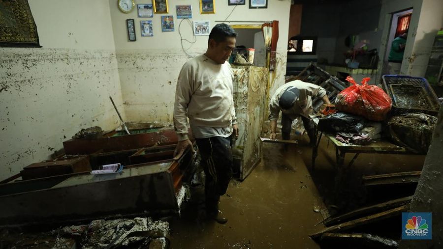 Warga membersihkan sisa-sisa lumpur dan sampah banjir yang melanda Kampung Pensiunan, Desa Tugu Selatan, Kecamatan Cisarua, Kabupaten Bogor, Jawa Barat, Senin (3/3/2025). (CNBC Indonesia/Tri Susilo)