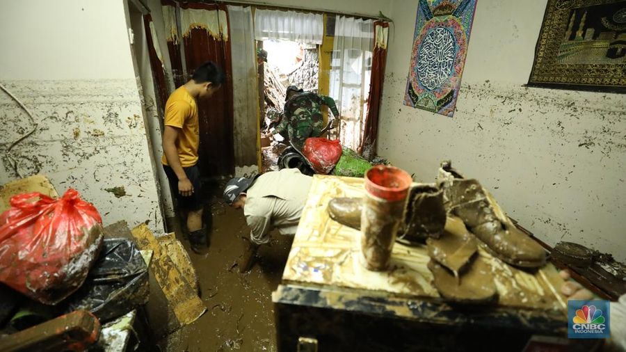 Warga membersihkan sisa-sisa lumpur dan sampah banjir yang melanda Kampung Pensiunan, Desa Tugu Selatan, Kecamatan Cisarua, Kabupaten Bogor, Jawa Barat, Senin (3/3/2025). (CNBC Indonesia/Tri Susilo)