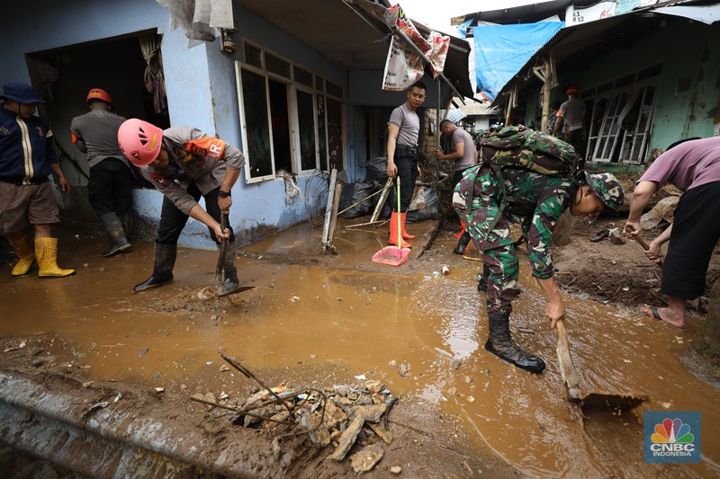 Warga membersihkan sisa-sisa lumpur dan sampah banjir yang melanda Kampung Pensiunan, Desa Tugu Selatan, Kecamatan Cisarua, Kabupaten Bogor, Jawa Barat, Senin (3/3/2025). (CNBC Indonesia/Tri Susilo)